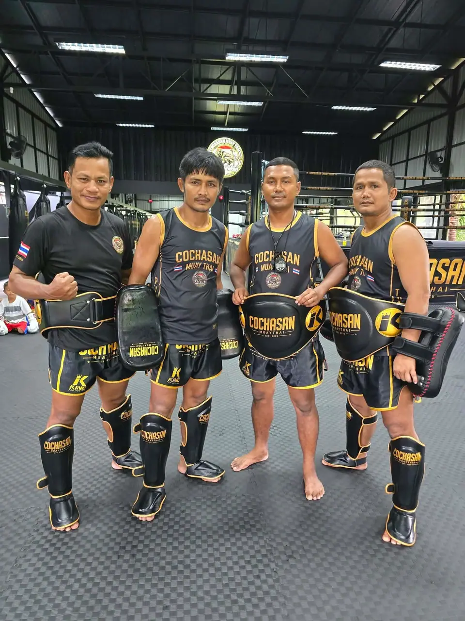The four COCHASAN coaches in full gym kit with pads and belly pads