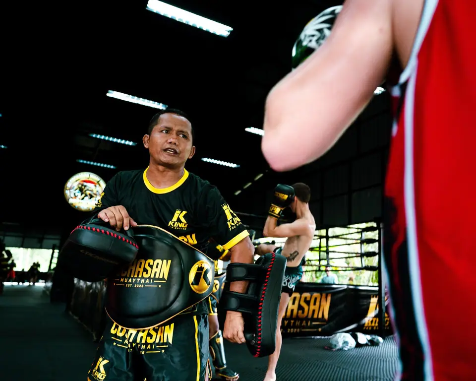 A Thai coach with belly pad and pads during a session
